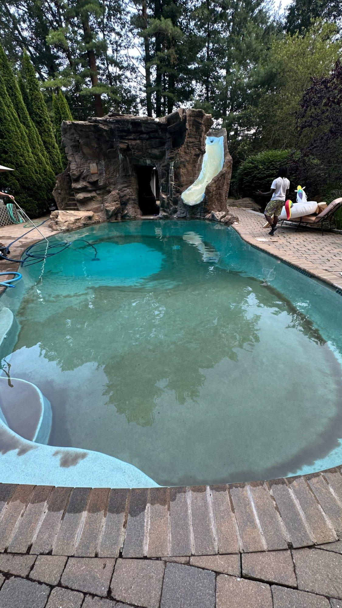 In-ground pool before maintenance — cloudy water with debris and algae on bottom